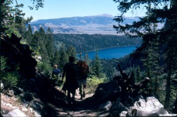 people on a trail with lake seen below them