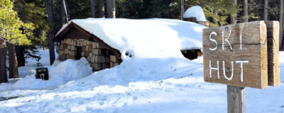 building in snow with ski hut sign beyond it