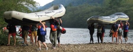 people wearing lifejackets carrying rafts