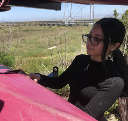 woman tightens strap on kayak that is on a trailer