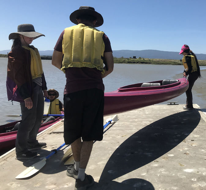 man and woman lifting kayak up off a dock to put it in the water