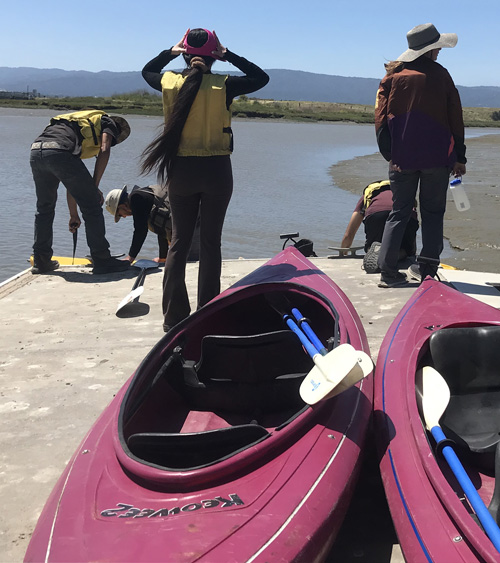 2 kayaks in foreground, people on deck behind