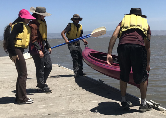two men lift a kayak up on to a dock