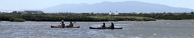 2 kayaks with two paddlers in each across and expanse of water