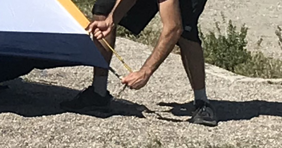 man putting end of tent pole into tent