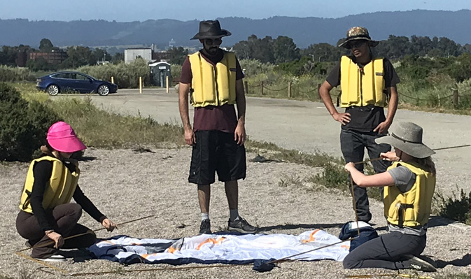 two people put shock- cord loaded poles together for tent