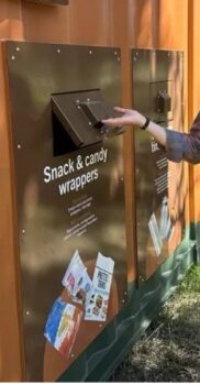 hand lifting door to recycling section labeled snack and candy wrappers