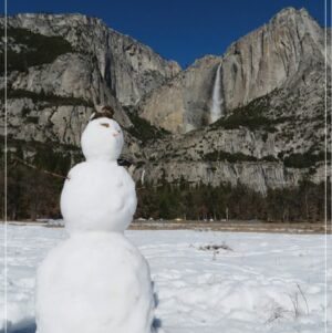 snowman in Cooks meadow yosemite with Yosemite Falls behind