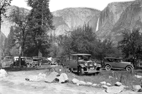 cars in foreground, waterfall from cliffs behind